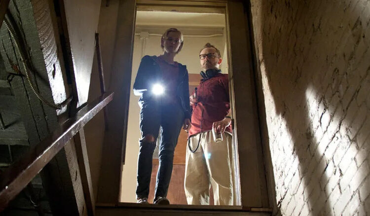 Claire and Luke peer down the stairs into the basement in The Innkeepers