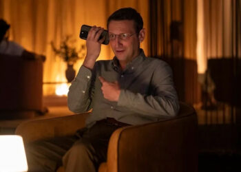 Ron on the phone pointing and making a weird face on The Chair Company