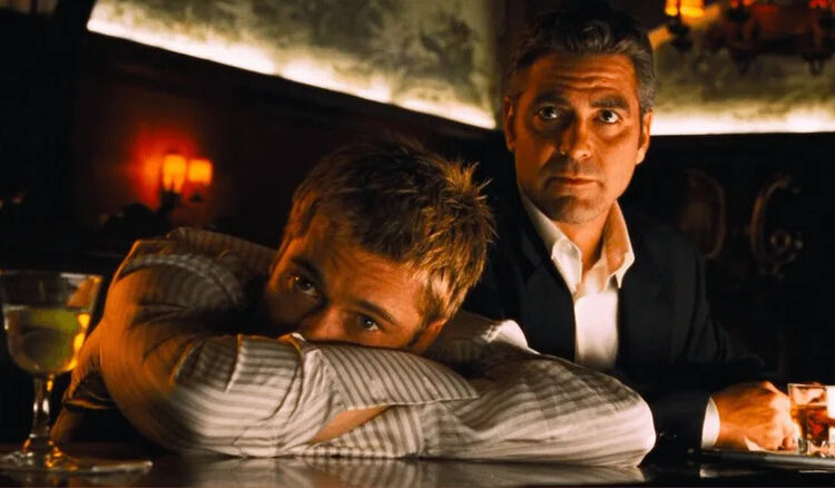 Rusty with his head in his arms at a bar top with Danny next to him in Ocean's Eleven