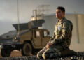 Major Daniel Gonzalez kneels in front of a military truck in "A House of Dynamite"