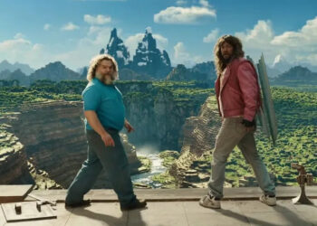 Jack Black and Jason Momoa both turn around to look back from the edge of a cliff in A Minecraft movie