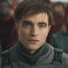 Robert Pattinson sits with a neutral expression in the sunlight in Mickey 17.