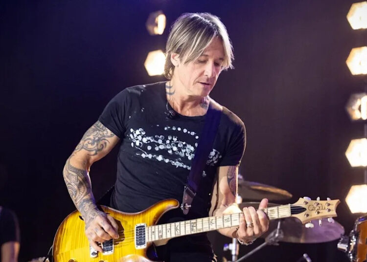Keith Urban playing the guitar in the series premiere of The Road on CBS.