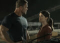 Alan Ritchson as Jack Reacher standing next to Sonya Cassidy as Susan Duffy in front of a table full of guns in Reacher