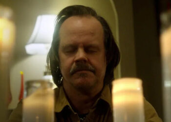 Jacob Lewis sitting at a candle altar in "We Are Still Here"