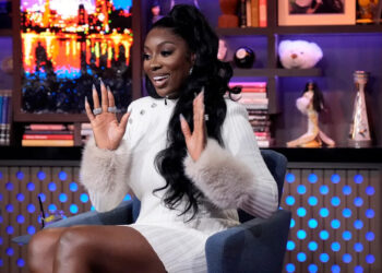 Wendy Osefo raising her hands and wearing a white dress on Watch What Happens Live