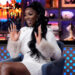 Wendy Osefo raising her hands and wearing a white dress on Watch What Happens Live