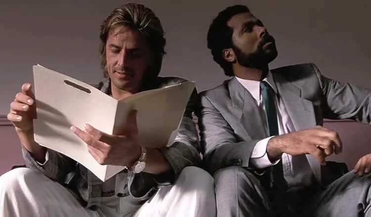 Don Johnson as Sonny Crockett and Philip Michael Thomas as Ricardo Tubbs sit next to each other in Miami Vice