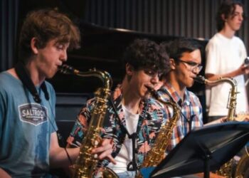 Three young people playing saxophone on stage