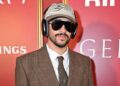Bad Bunny wearing a brown suit posing for the camera.