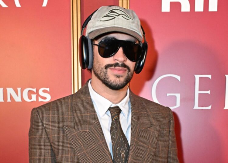 Bad Bunny wearing a brown suit posing for the camera.