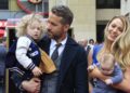 Blake Lively walking down the street with her husband Ryan Reynolds and their four children, dressed casually and smiling.