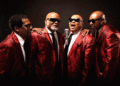 The four Blind Boys of Alabama, wearing shiny red suit jackets, black ties and white shirts, sing in front of a microphone. (Courtesy photo)