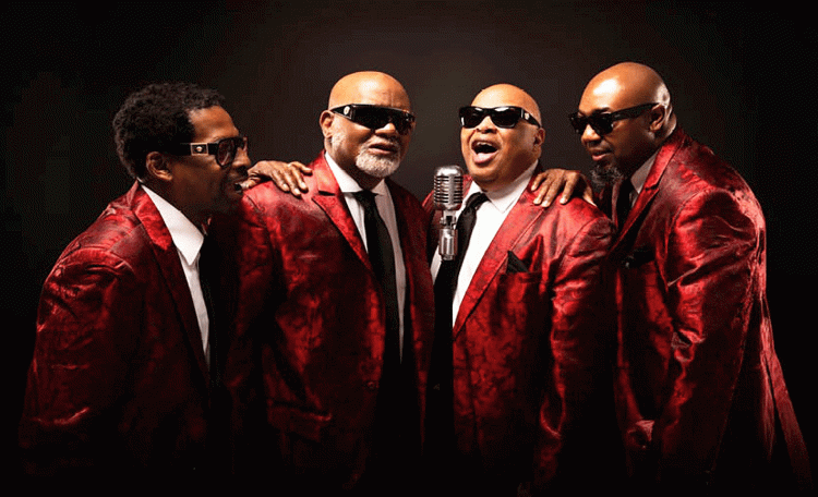 The four Blind Boys of Alabama, wearing shiny red suit jackets, black ties and white shirts, sing in front of a microphone. (Courtesy photo)