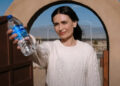 A woman offers a bottle of water in Pluribus