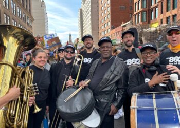 AFM Local 802 musicians marching in a parade with instruments and wearing "Local 802 AFM" hats and shirts.
