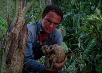 Burt Reynolds as Douglas Temple holding a skull in Skullduggery