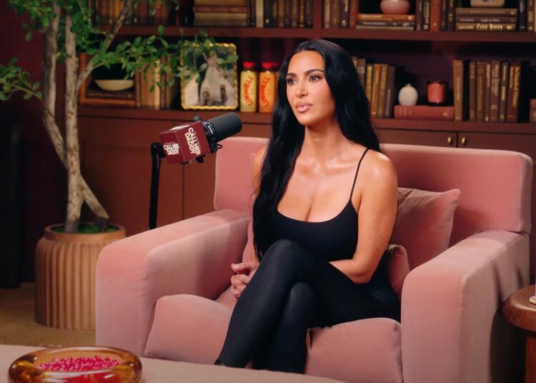 Kim Kardashian sits across from Alex Cooper in the Call Her Daddy studio, engaged in a candid conversation surrounded by soft studio lighting and microphones.