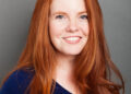 Photo: A young woman with bright auburn hair, wearing a navy shirt.