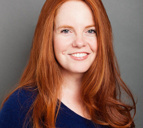 Photo: A young woman with bright auburn hair, wearing a navy shirt.
