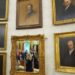 As reflected in a mirror, President Donald Trump speaks to reporters before signing an executive order in the Oval Office at the White House, Monday, Oct. 6, 2025, in Washington. (AP Photo/Jacquelyn Martin)