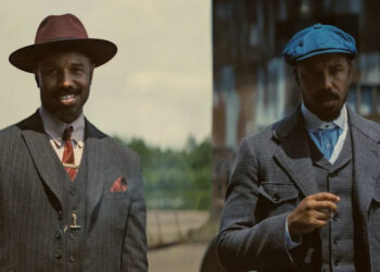 Twin Michael B Jordans stand together against in front of the old saw mill in Sinners.
