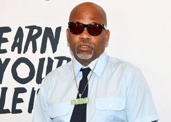 Damon Dash wearing sunglasses, a light blue shirt, and a necklace with