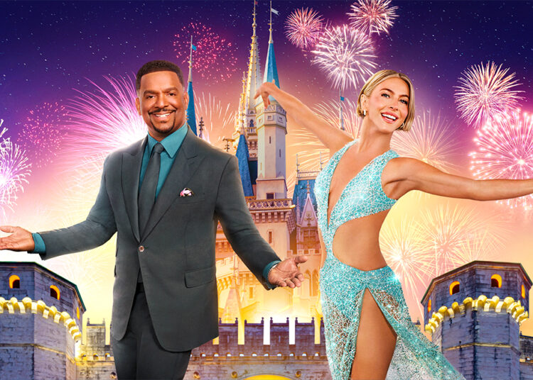 Dancing with the Stars cohosts Alfonso Ribeiro and Julianne Hough are seen in front of an image of a Disney park castle, with fireworks in the background; several fireworks on the right, behind Hough, are shaped like Mickey Mouse.