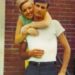 a younger dolly parton standing behind carl dean with her arms around his neck