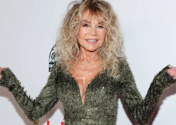 Dyan Cannon shrugging in a sparkling green dress.