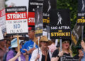 Members of the Hollywood's actors and writers unions walk with signs in Los Angeles, California. They wave signs that say "On Strike" and others blasting AI.