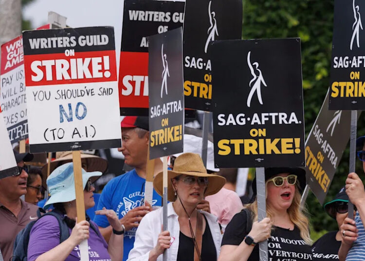 Members of the Hollywood's actors and writers unions walk with signs in Los Angeles, California. They wave signs that say "On Strike" and others blasting AI.
