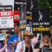 Members of the Hollywood's actors and writers unions walk with signs in Los Angeles, California. They wave signs that say "On Strike" and others blasting AI.