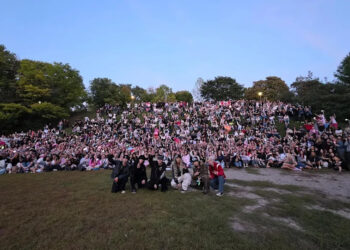 P1Harmony take a group photo with hundreds of fans during a fan meeting at Trinity Bellwoods Park.