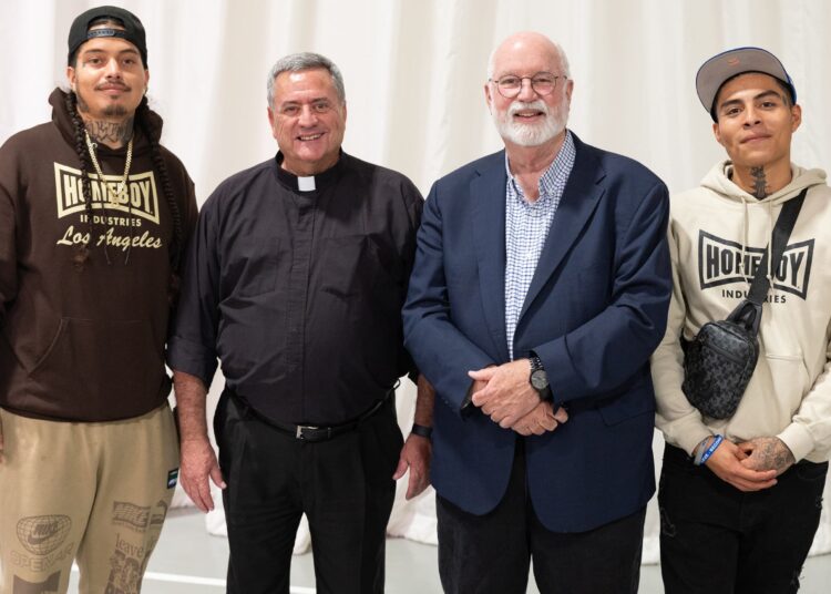 Four individuals stand together smiling for a group photo.