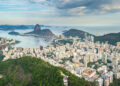 An landscape shot from atop a mountain onto the sea-side city below.