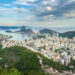 An landscape shot from atop a mountain onto the sea-side city below.