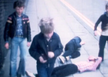Still of a cine film showing five teenagers (left to right) Ian Sallery, Paul Birchall, Paul Sudbury, John Tyson, and Tony Gandy - with two lying on the pavement - after a fight scene - filmed in 1978.