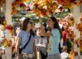 A photo of two women in a gazebo with fall decor strung up on the structure.