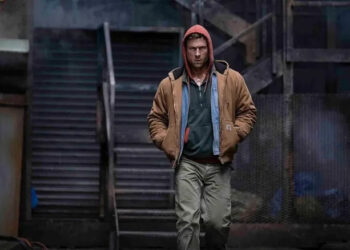 Glen Powell as Ben Richards walking and wearing a hoodie in The Running Man (2025)