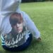 child sitting on grass wearing a hoodie with a graphic design