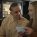 Charlie Hunnam as Ed Gein seated next to Suzanna Son as Adelina in a diner booth in Monster: The Ed Gein Story