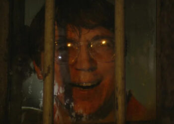 Paul Dano as the Riddler smiling behind bars in The Batman