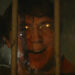 Paul Dano as the Riddler smiling behind bars in The Batman