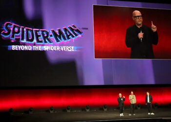 Three people on stage at a Spider-Man: Beyond the Spider-Verse event, with a large screen displaying the title.