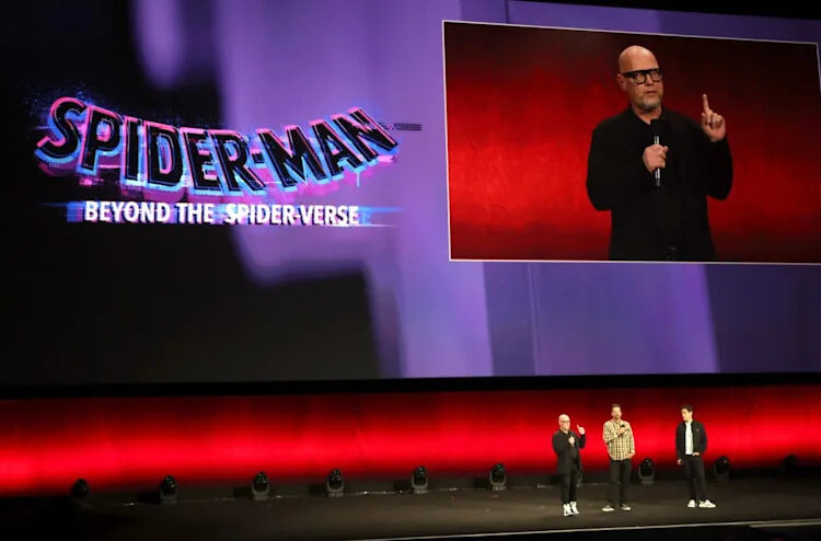 Three people on stage at a Spider-Man: Beyond the Spider-Verse event, with a large screen displaying the title.