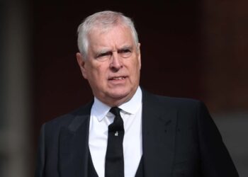 A medium shot of Prince Andrew wearing a black suit and tie