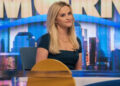 Reese Witherspoon sitting at the desk of The Morning Show.