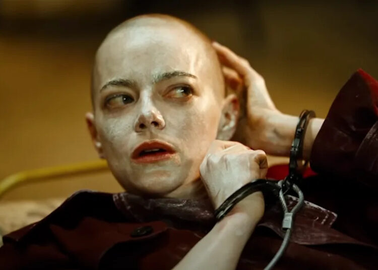 Emma Stone bald and handcuffed with white cream all over her face and head in Bugonia.