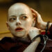 Emma Stone bald and handcuffed with white cream all over her face and head in Bugonia.